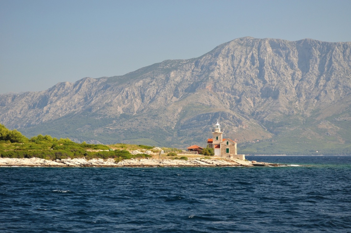 Lighthouse on south end of island Hvar in Adriatic sea with mountain Biokovo in background. Sucuraj, Croatia
